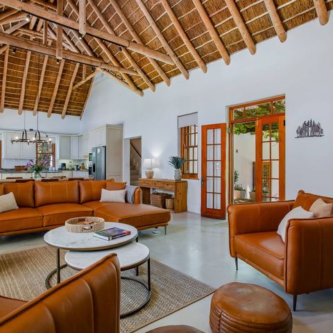 Living room with thatched ceiling, leather seating and wood-burning stove
